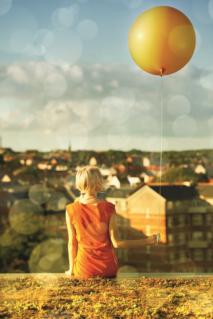 Une femme un ballon à la main regarde un paysage urbain